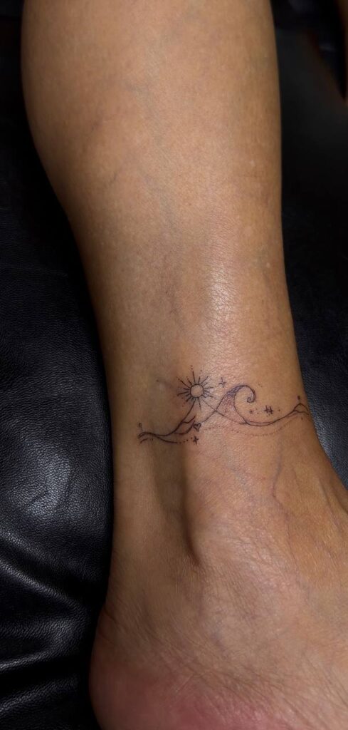 Fine Line Tattoo am Knöchel: Welle mit Sonne und Sternen