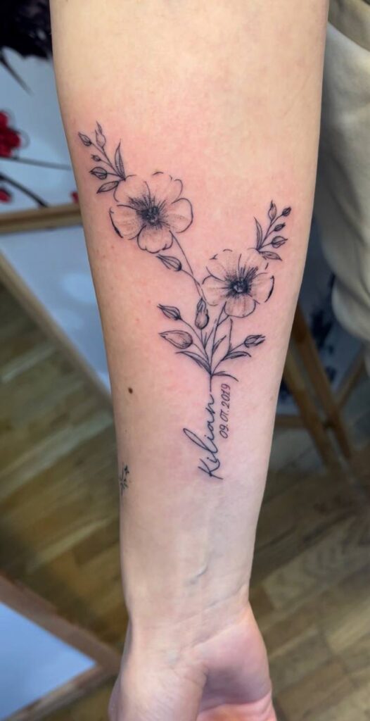 Blumenzweig mit Namen und Datum am Unterarm