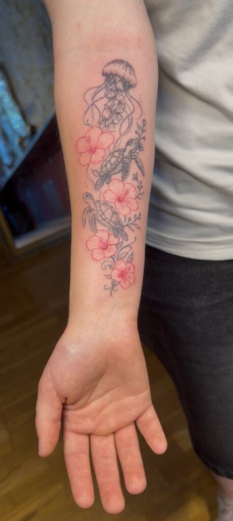 Hibiskusblüten mit Qualle und Schildkröten am Unterarm, mit Farbakzenten