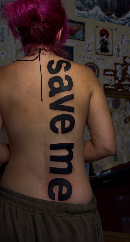 Großer Schriftzug „save me“ in fetter Schrift entlang der Wirbelsäule