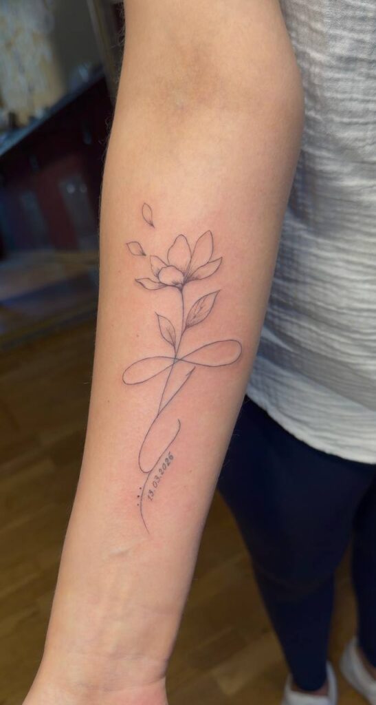 Lotusblüte mit Unendlichkeitszeichen und Datum am Unterarm