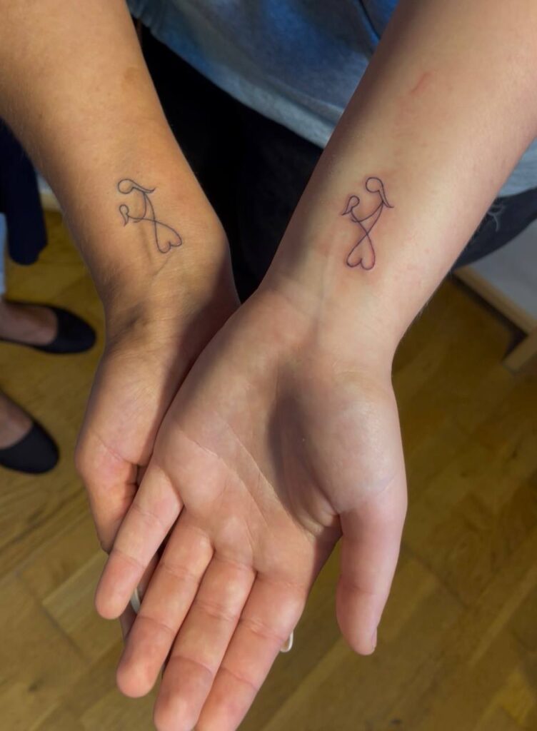 Partner-Tattoos am Handgelenk: verbundene Figuren mit Herz