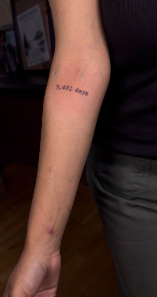 Schriftzug „5,481 days“ in Schreibmaschinenschrift am Unterarm
